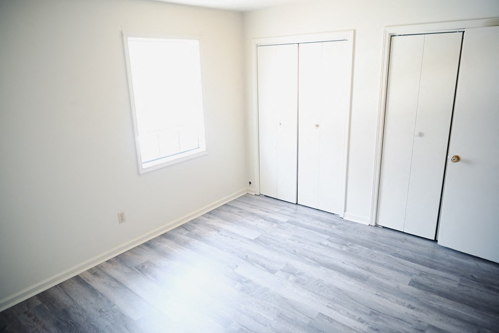 an empty room with white walls and wood floors