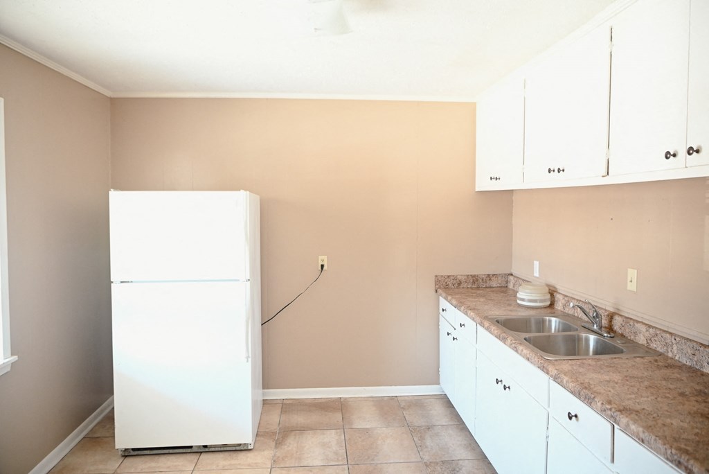 an empty kitchen with white cabinets and a white refrigerator