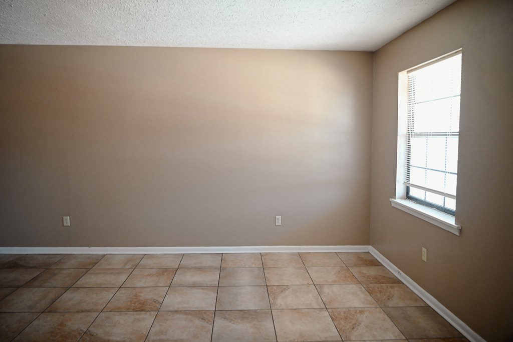 an empty room with a window and a tiled floor