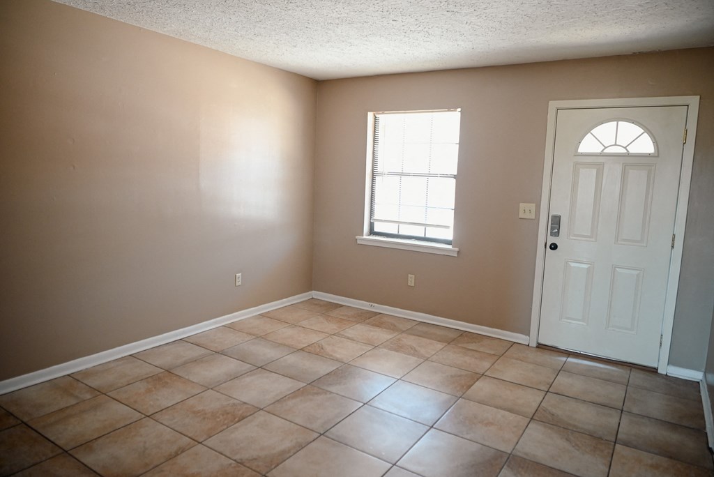 an empty living room with tiled floors and a white door