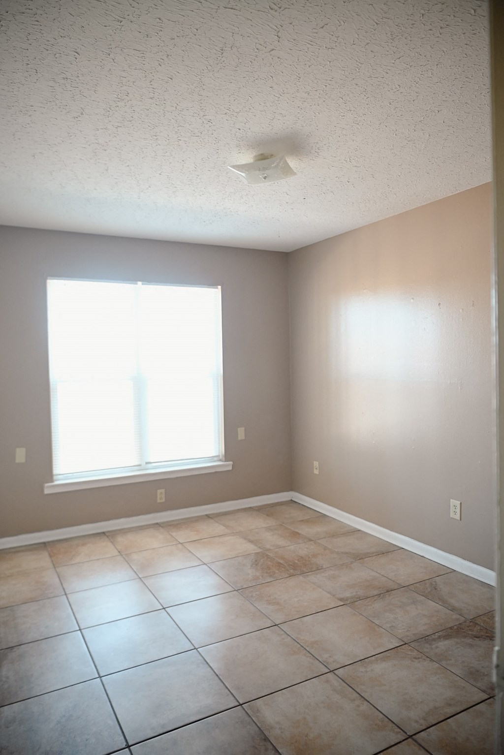 an empty living room with tiled floors and a window