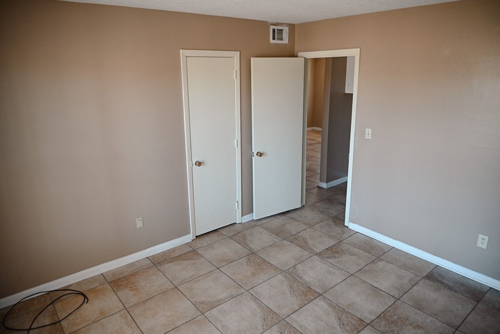 an empty room with a tiled floor and two closet doors