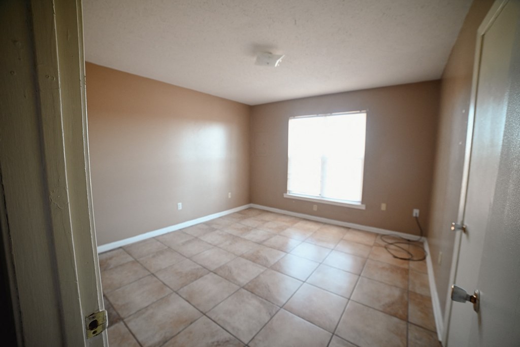 an empty living room with tiled floors and a window