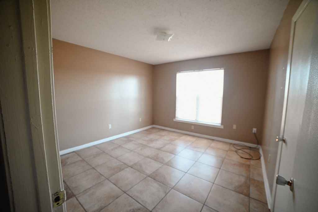 an empty living room with tiled floors and a window