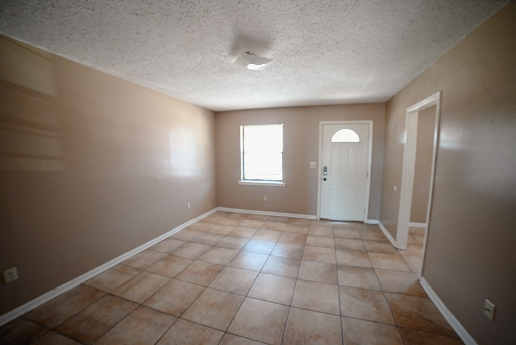 an empty living room with tile floors and a white door