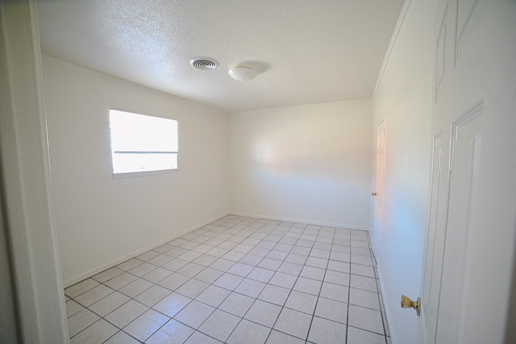 an empty room with a tile floor and a window