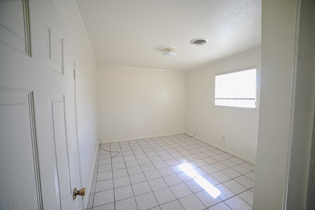 an empty room with a tile floor and a window
