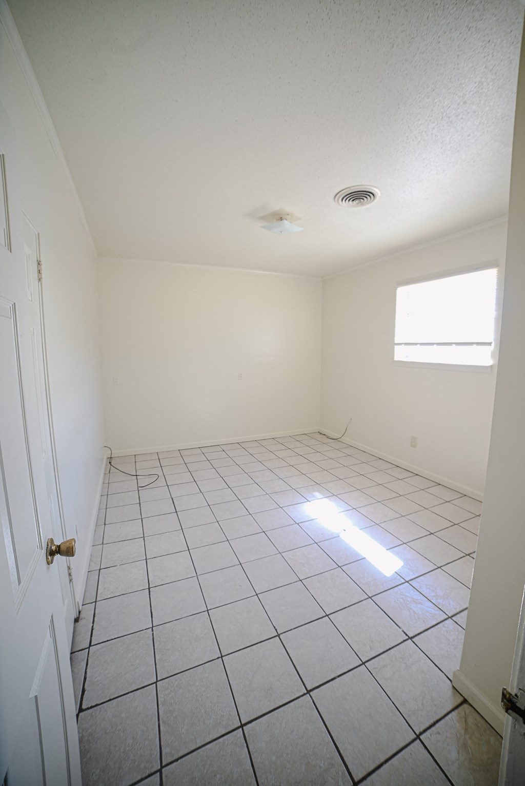 an empty room with a tiled floor and a window
