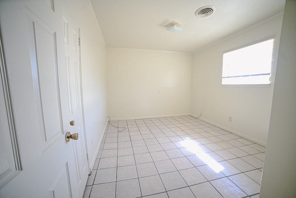 an empty room with a tile floor and a window