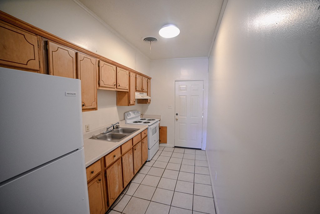 an empty kitchen with a refrigerator stove and sink