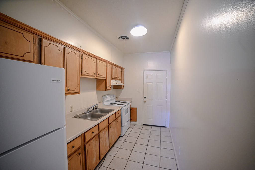 an empty kitchen with a refrigerator and a sink