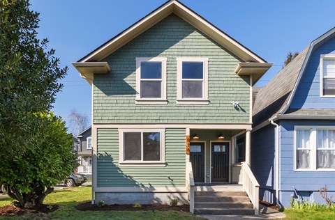 the front of a green house with a blue sky background