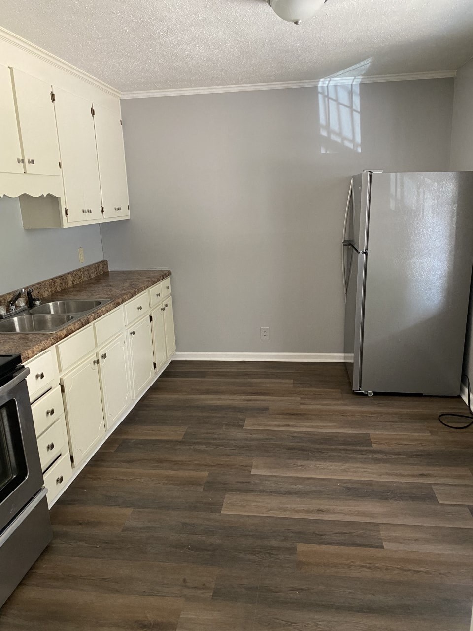 a kitchen with white cabinets and a stainless steel refrigerator