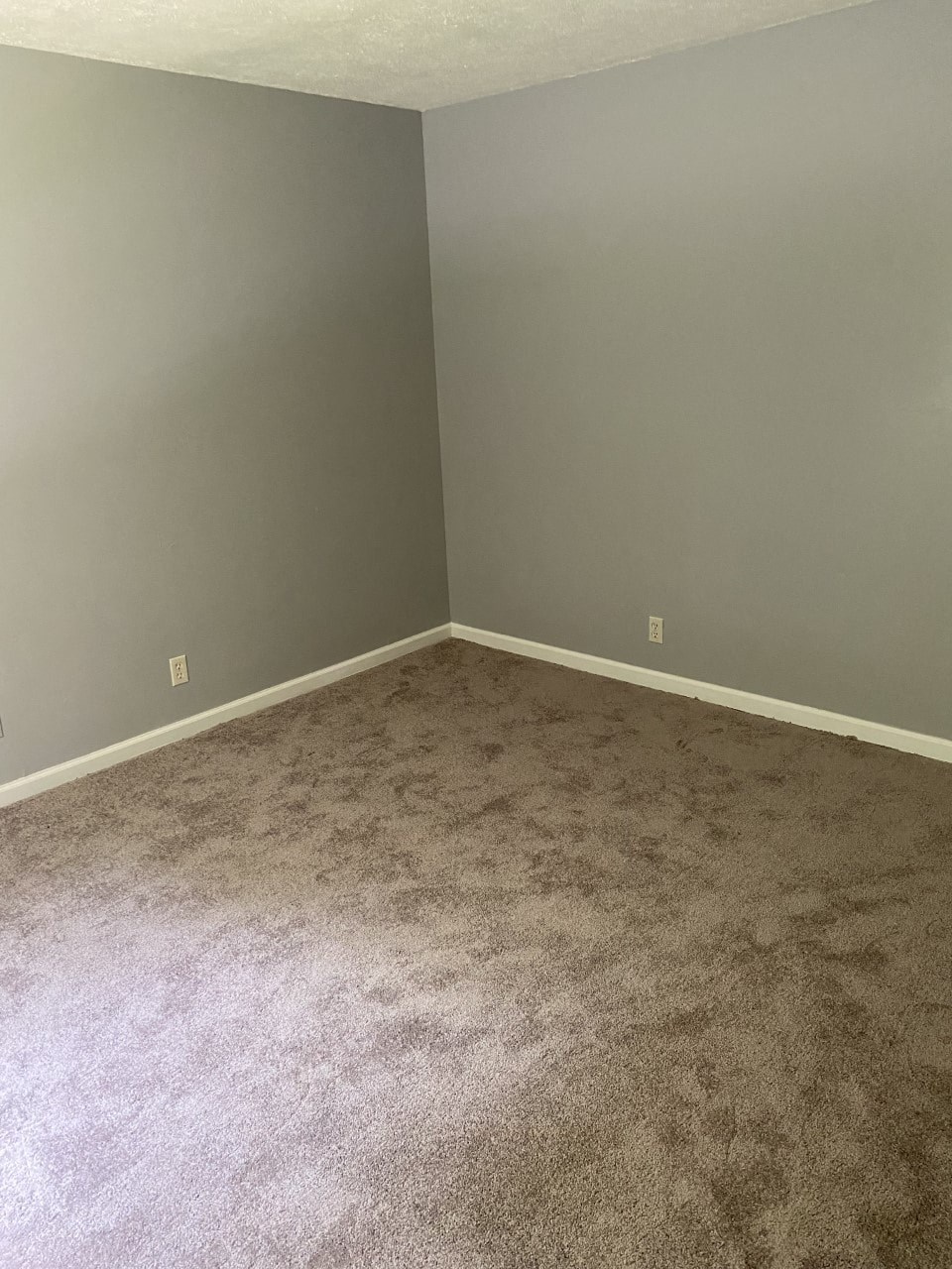 a empty room with a carpeted floor and gray walls