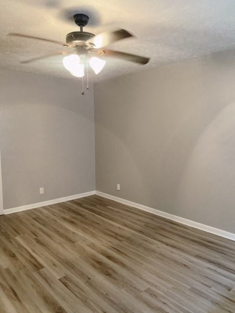 an empty room with a ceiling fan and wood floors