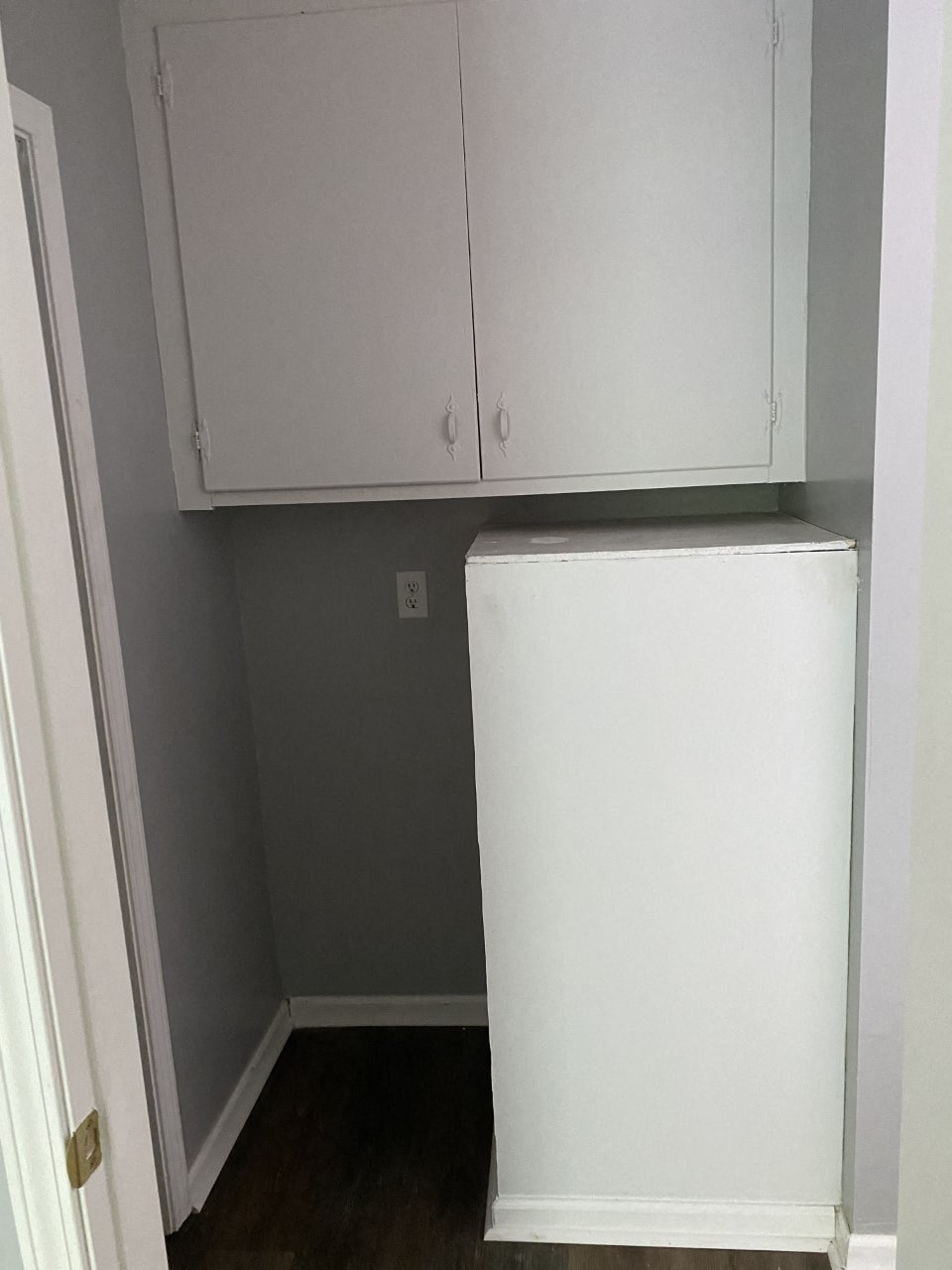 a small closet with white cabinets and a white refrigerator