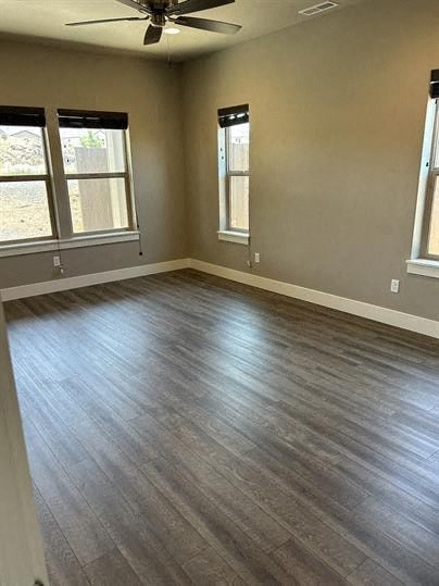 A room with a ceiling fan and wood flooring.