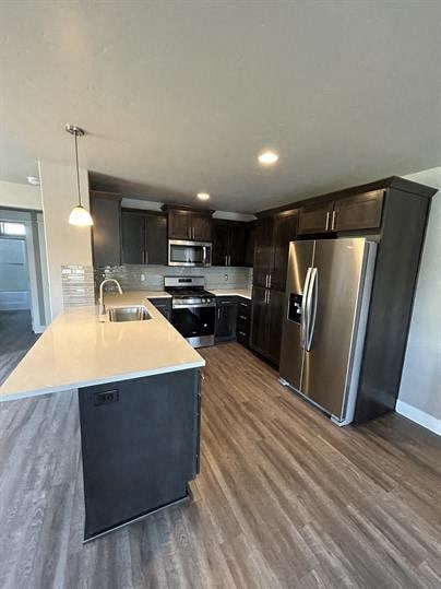 A modern kitchen with dark wood cabinets and stainless steel appliances.
