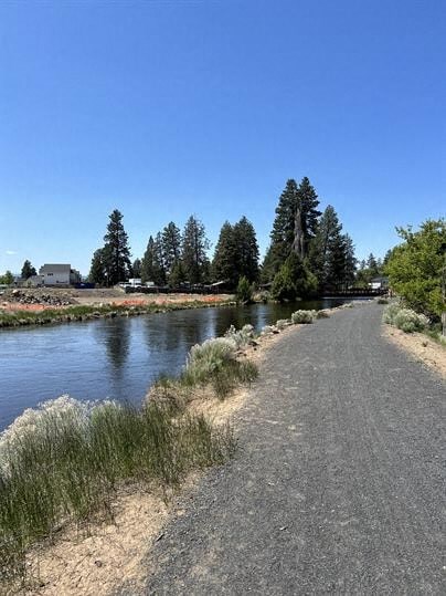 A path runs parallel to a body of water with trees in the background.