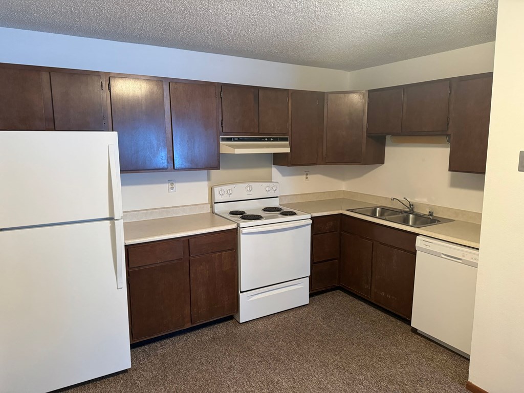 an empty kitchen with white appliances and wooden cabinets