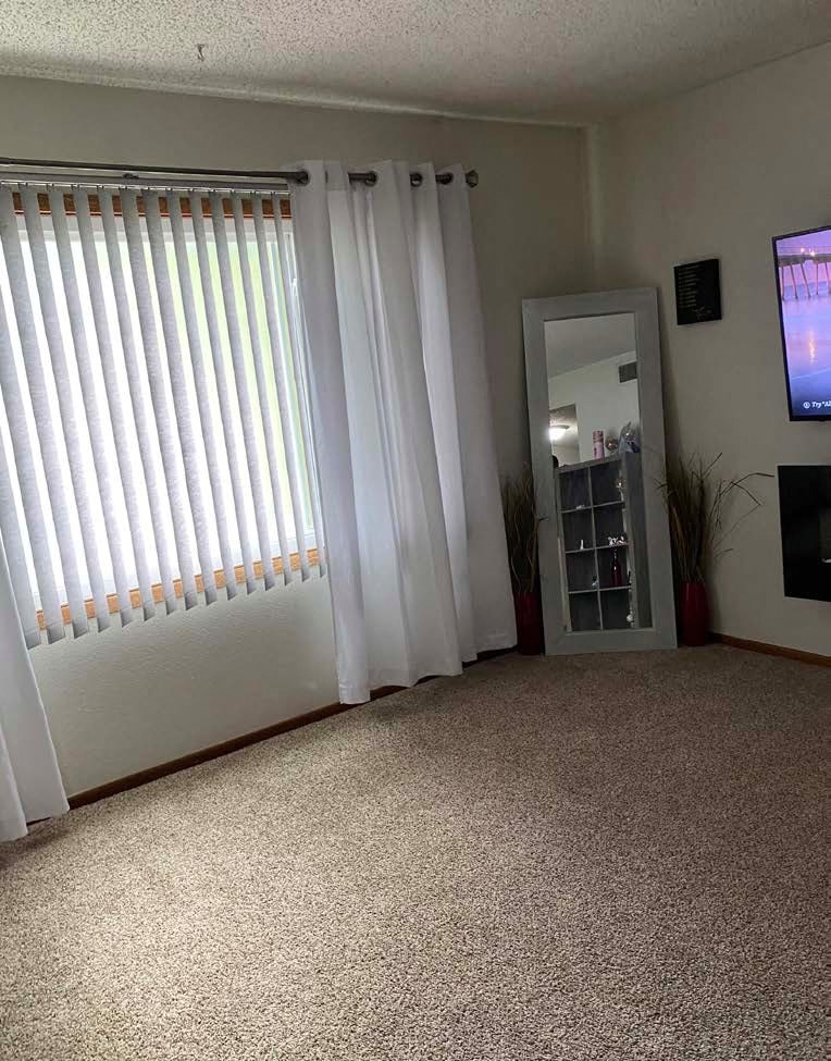 a room with white blinds on the window and a door