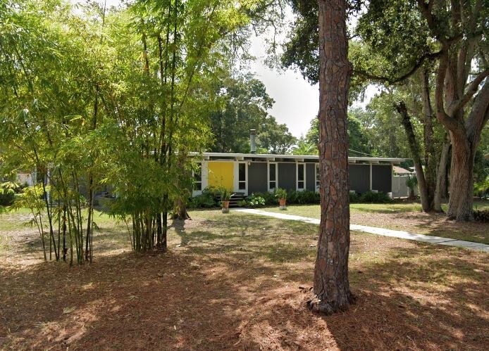 a house with a yard and trees in front of it