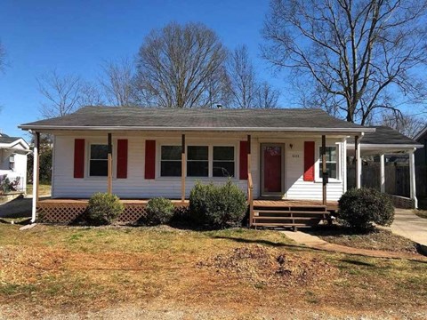 A small white house with red trim and a red door.