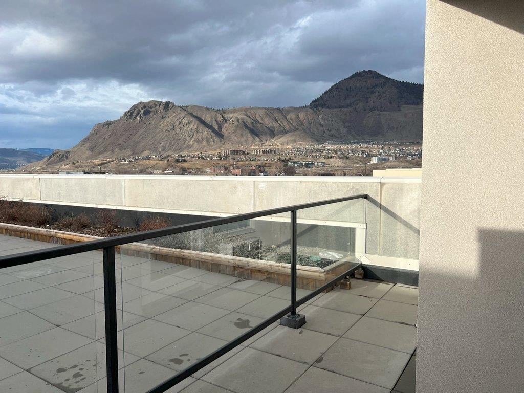 a balcony with a view of a mountain and a cloudy sky