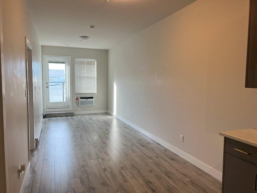 a empty living room with wood floors and a door to a balcony