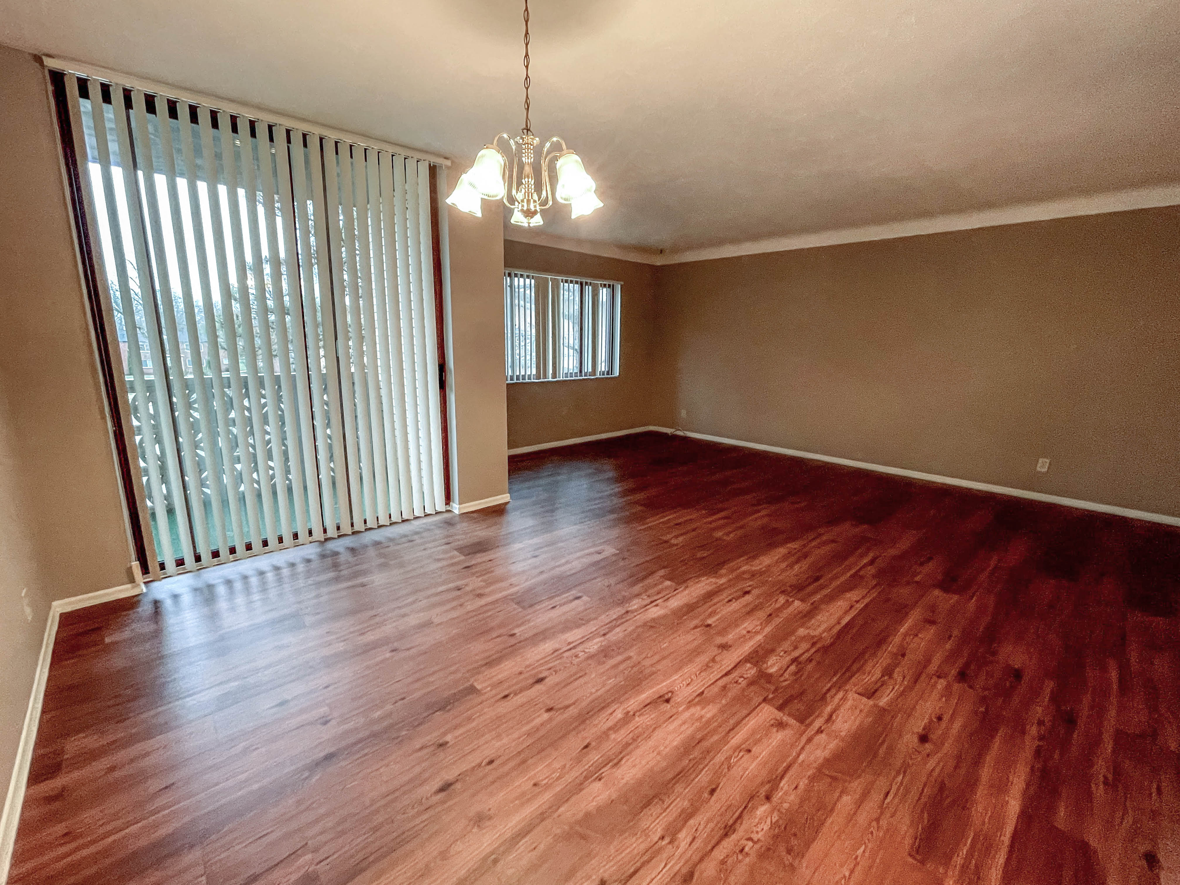 an empty living room with a hard wood floor and a window
