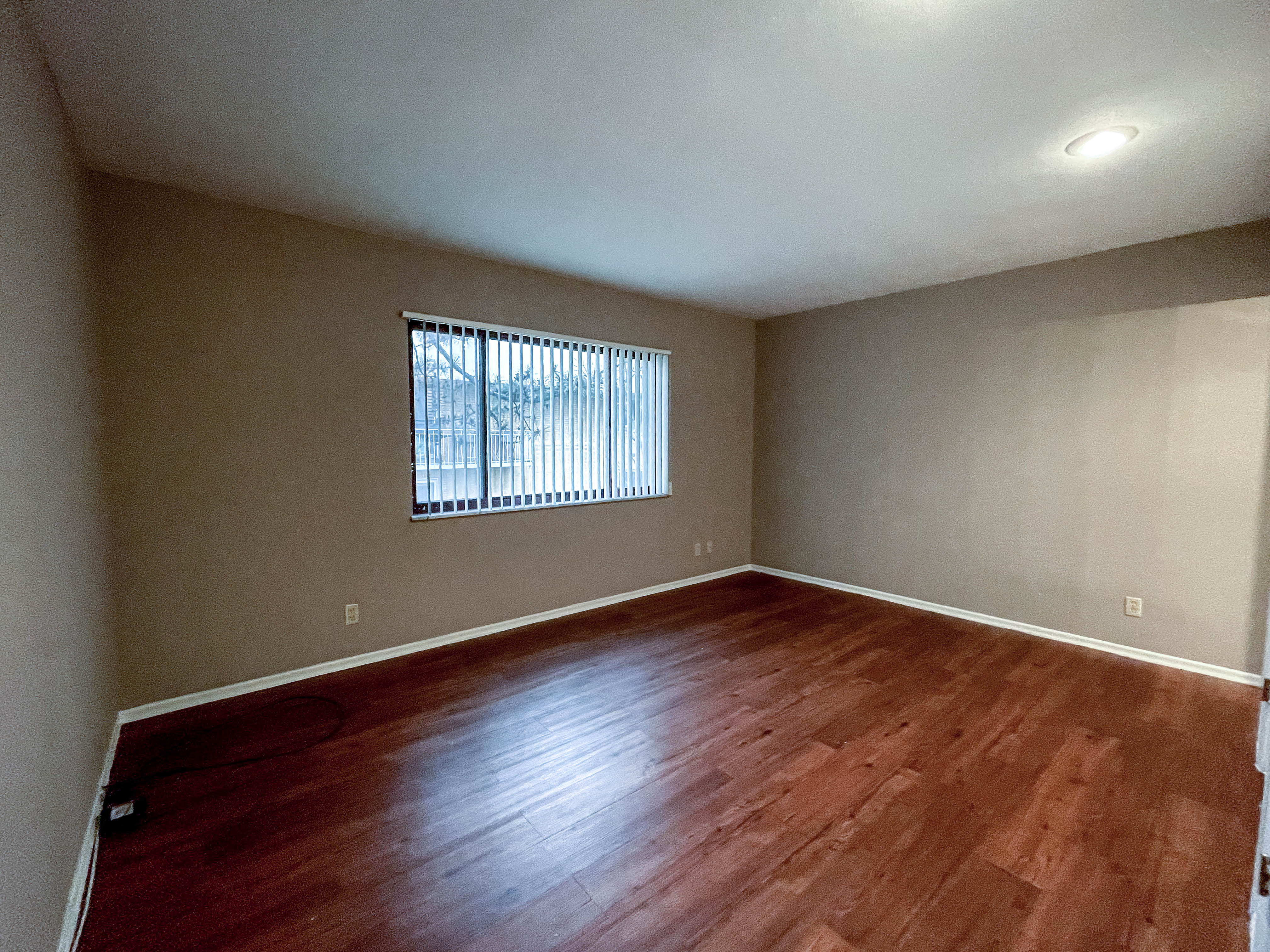 an empty living room with wood floors and a window