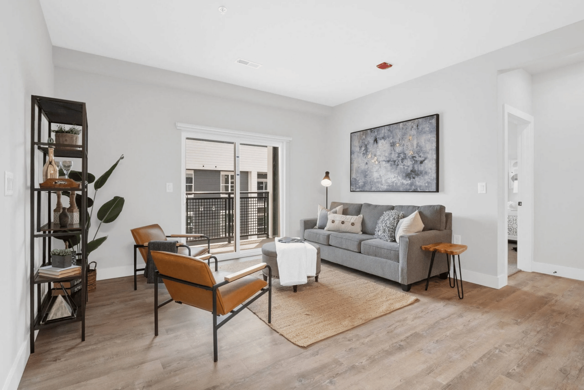 A living room with a grey couch, a brown chair, and a large painting on the wall.