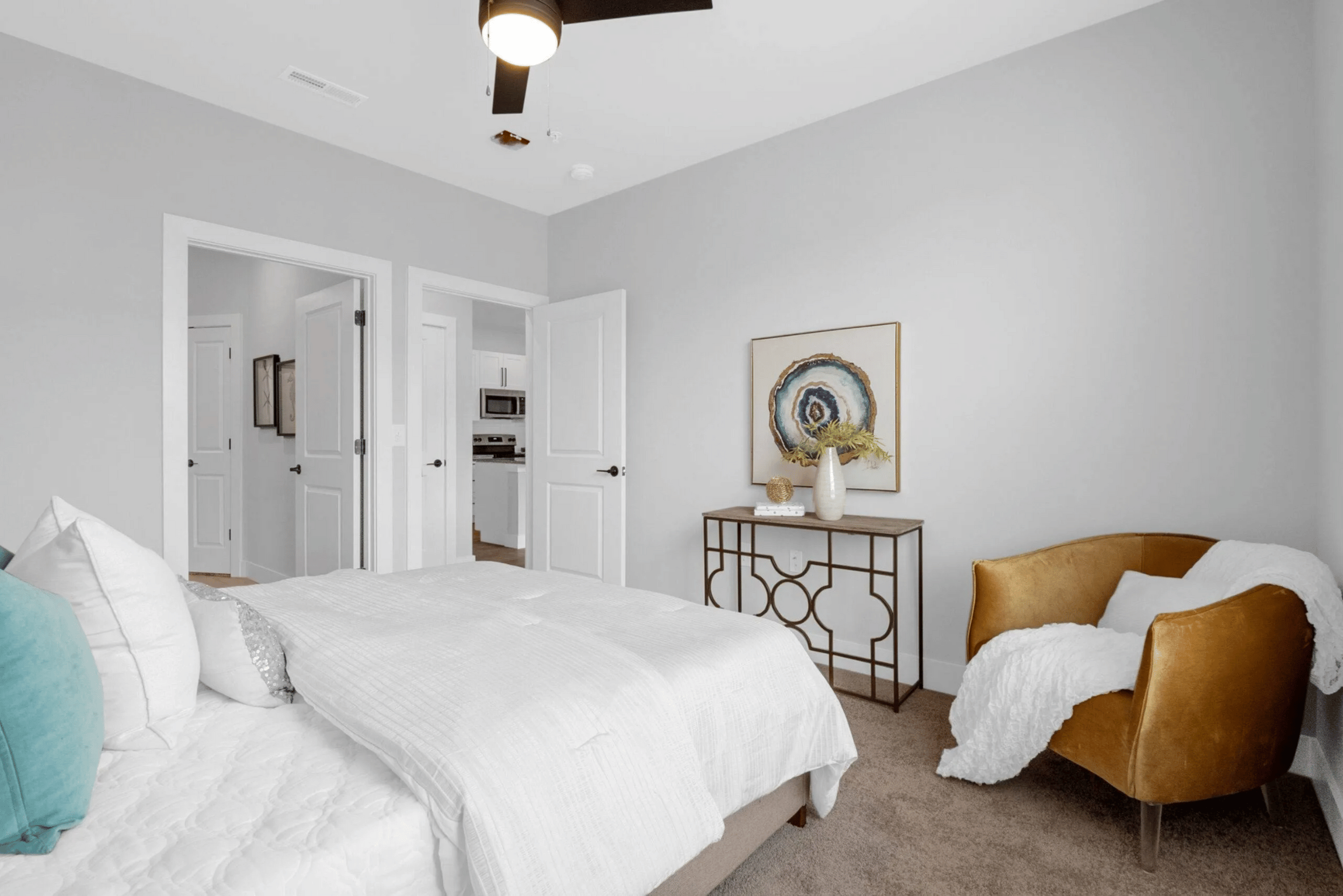 A bedroom with a white bed and a brown chair.