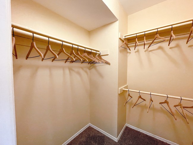 a walk in closet with hangers and a mirrored closet wall