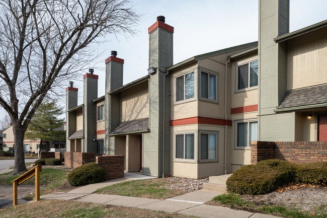 a row of multifamily buildings with chimneys and a sidewalk