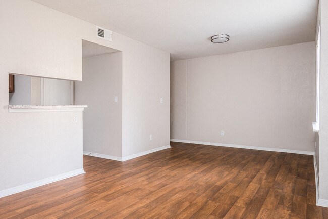 an empty living room with wood floors and white walls