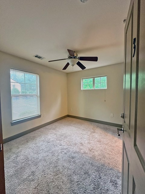 an empty room with a ceiling fan and a window