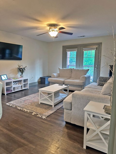 a living room with a ceiling fan and a tv