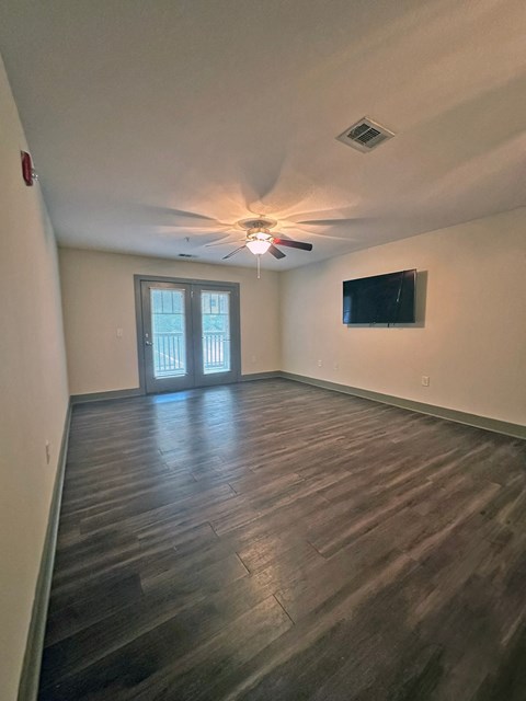 an empty living room with wood floors and a ceiling fan