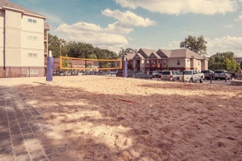 a sandy area in front of a building with a volleyball court
