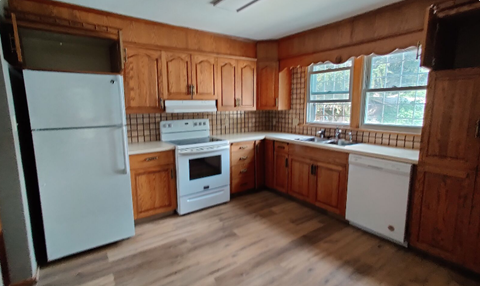 A kitchen with wooden cabinets and white appliances.