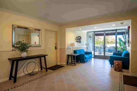 A living room with a mirror, a blue sofa, and a table with a vase of flowers.