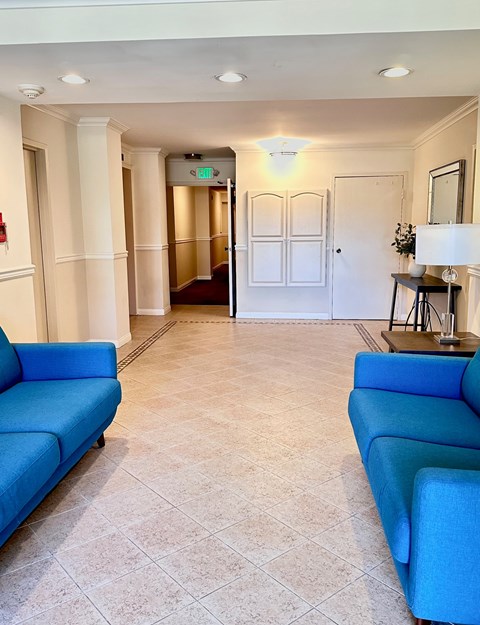 A hallway with blue couches and a white door.