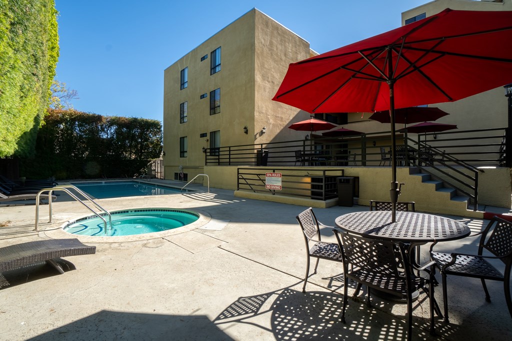 A red umbrella is on a table outside a building.