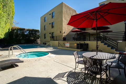 A red umbrella is on a table outside a building.