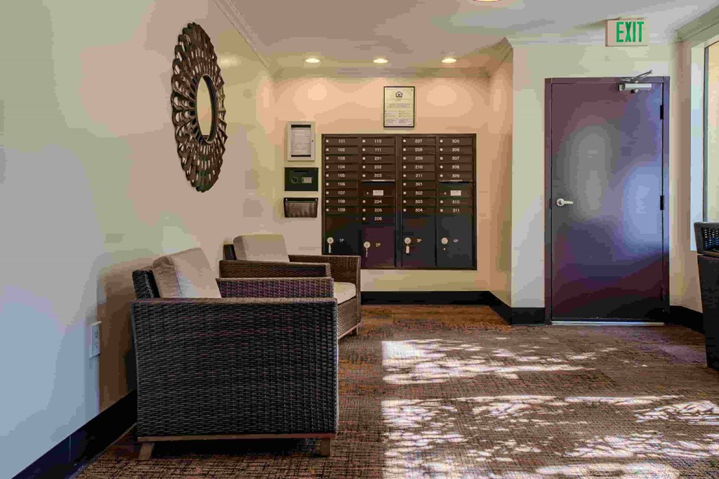 A room with a couch, a mirror, and a wall with a clock.