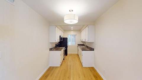 a renovated kitchen with white cabinets and wood floors