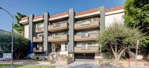a large apartment building with a driveway and trees
