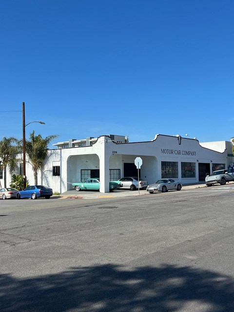 A car dealership with a white building and cars parked outside.