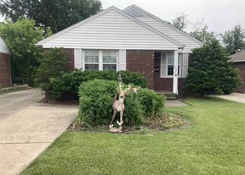 A statue of a deer stands in the front yard of a house.